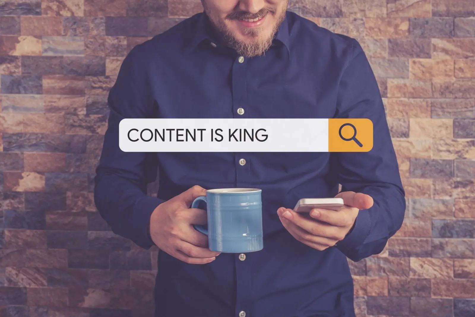 A man leans against a brick wall holding a coffee mug and his phone with a search bar reading “Content is King” superimposed across the image.