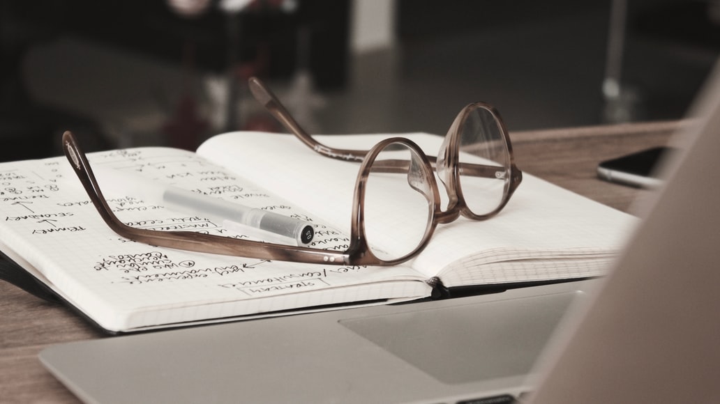 A pair of glasses on top of a notebook.