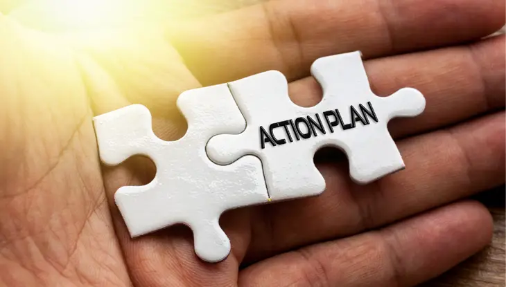 hand holding two white interlocking puzzle pieces with words “action plan” on them